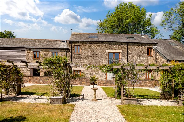 Threshing g Barn extra with stone walls and slate roof with garden in the foreground.